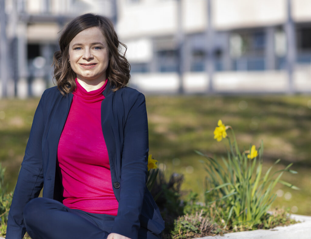 Anna auf dem PTB-Gelände mit frühlingshaften Blumen im Hintergrund.