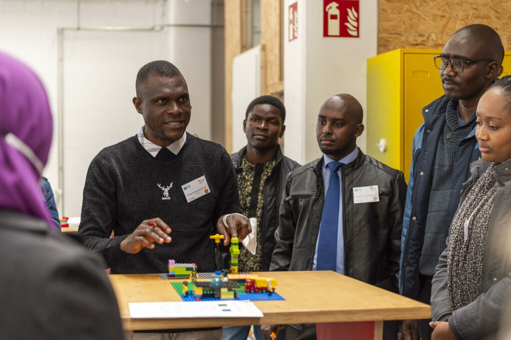 A man and a woman stand in front of a table with Lego bricks