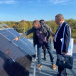 Deux hommes se tiennent devant des panneaux solaires. L'un d'eux pointe le module.