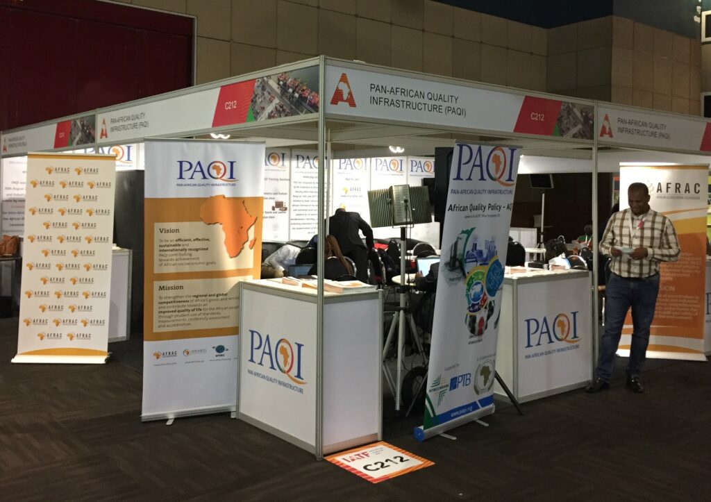 In einer Messehalle steht der Stand der Pan-African Quality Infrastructure (PAQI) mit zahlreichen Informationsangeboten in Form von Flyern und Aufstellern.