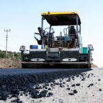 Black slag in front of an excavator.