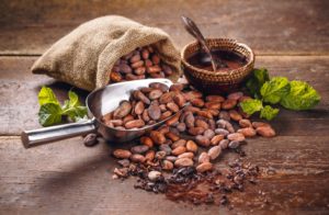 Cocoa beans pouring from a sack onto a wooden table.