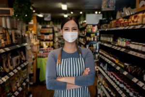 A woman wearing an apron and a face mask while working the supermarket.