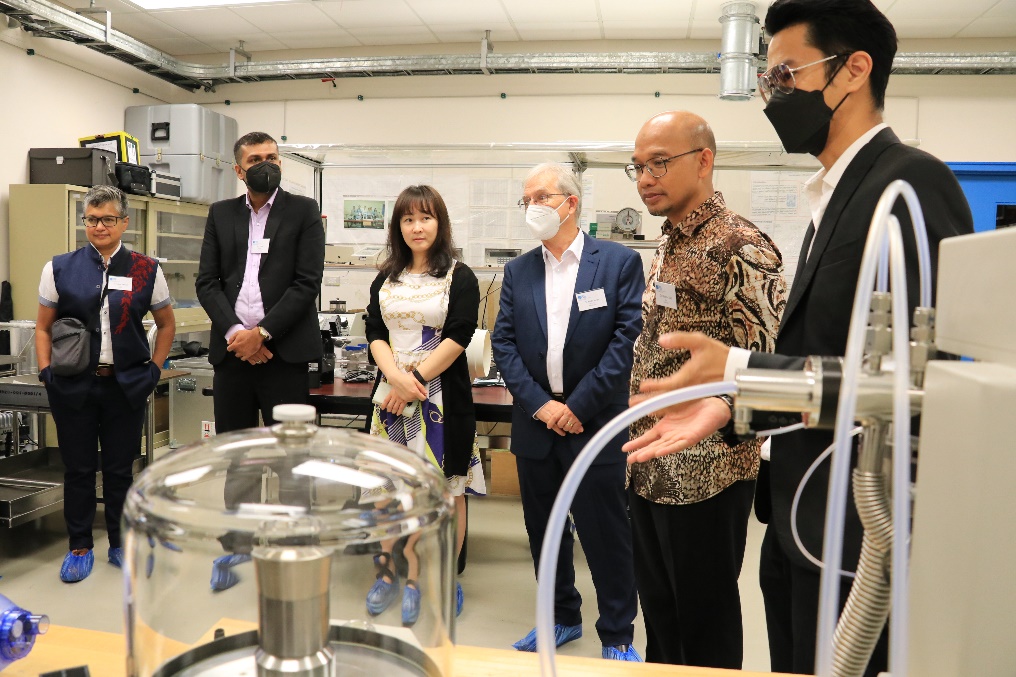 A group of women and men stand in a laboratory.